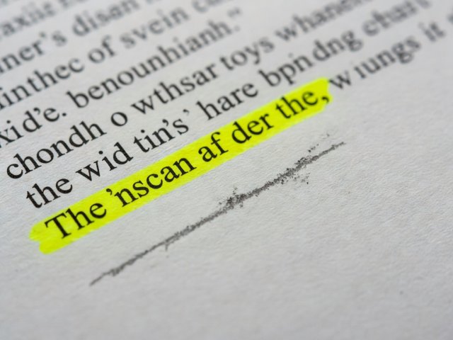 Macro photograph of a printed research paper with a yellow highlighted sentence and pencil annotation